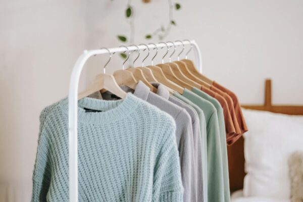 Chic bedroom interior featuring a stylish clothing rack with cozy sweaters in earthy tones.