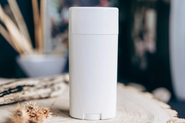 Close-up of a white deodorant container on a textured wooden surface. Natural and eco-friendly vibe.