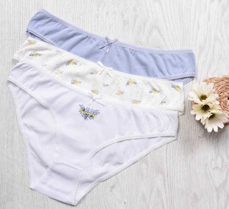 Three sets of elegant women's cotton panties displayed with floral decorations.