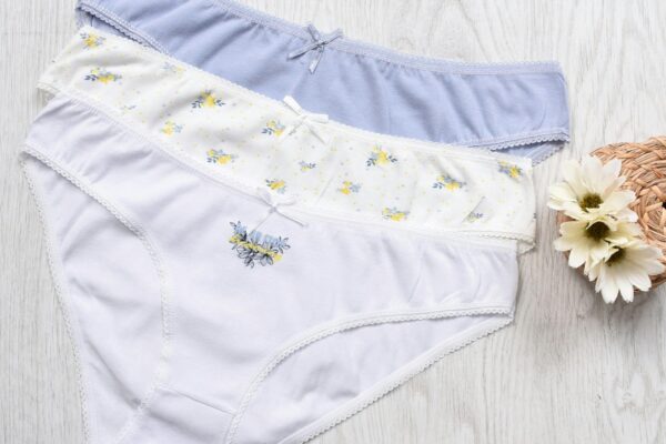 Three sets of elegant women's cotton panties displayed with floral decorations.