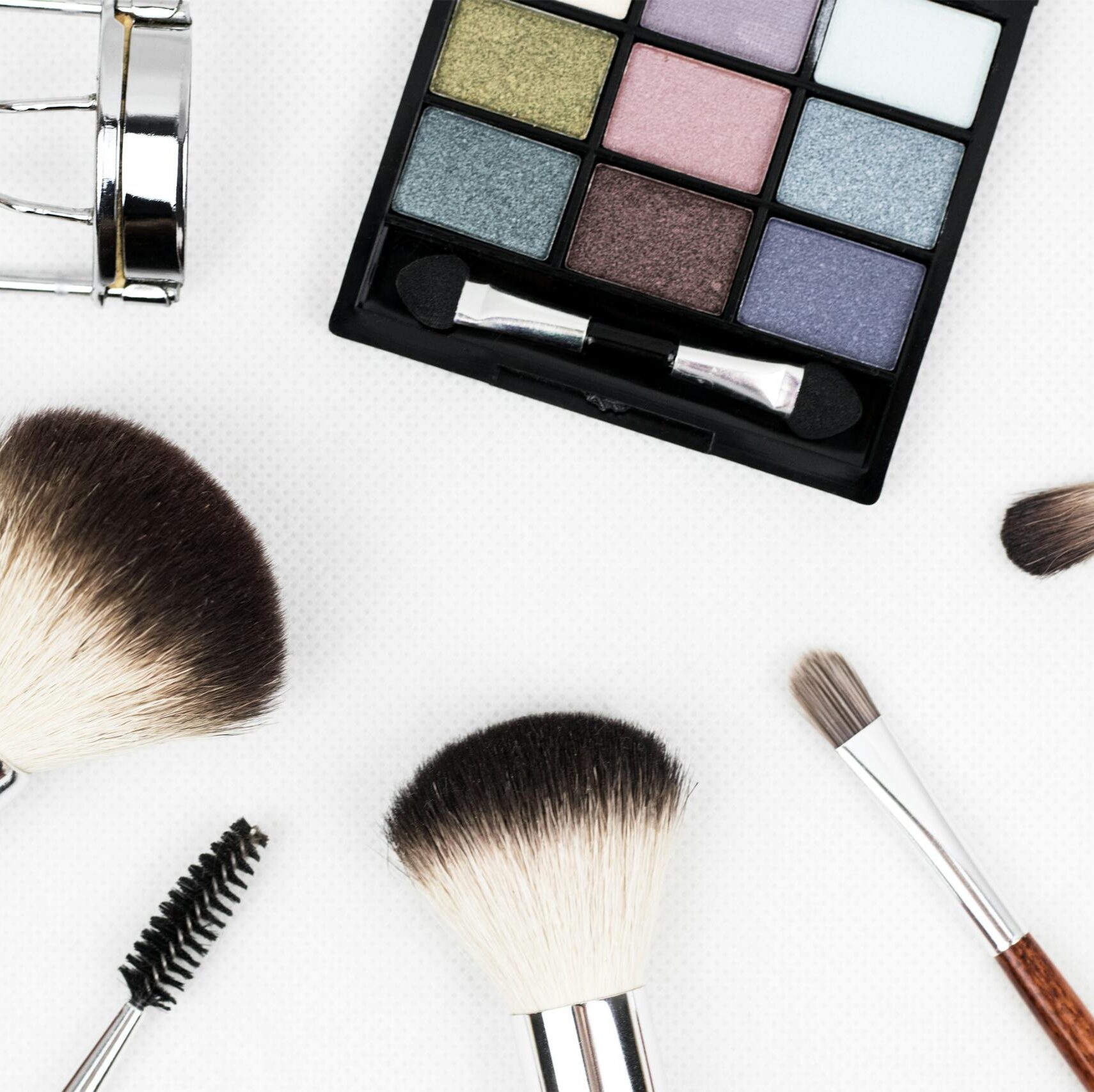 Top view of makeup tools and a colorful eyeshadow palette arranged artistically.