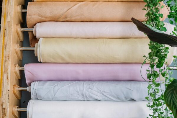 Vertical shot of vibrant fabric rolls in a tailor shop with greenery.