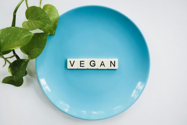 A blue plate with the word 'VEGAN' and a leafy plant, symbolizing a plant-based diet.