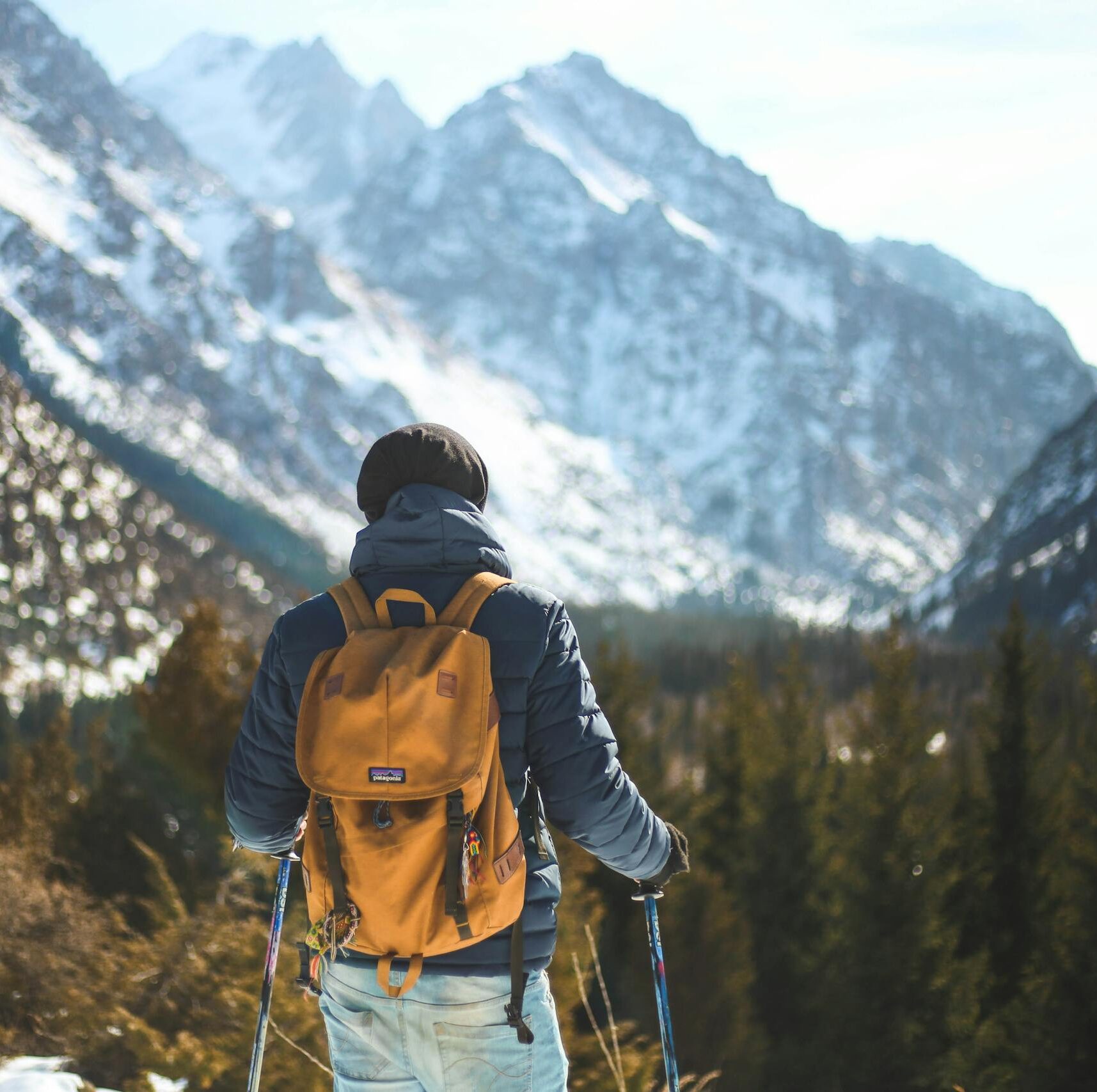 A lone hiker with a backpack explores a scenic winter mountain landscape.