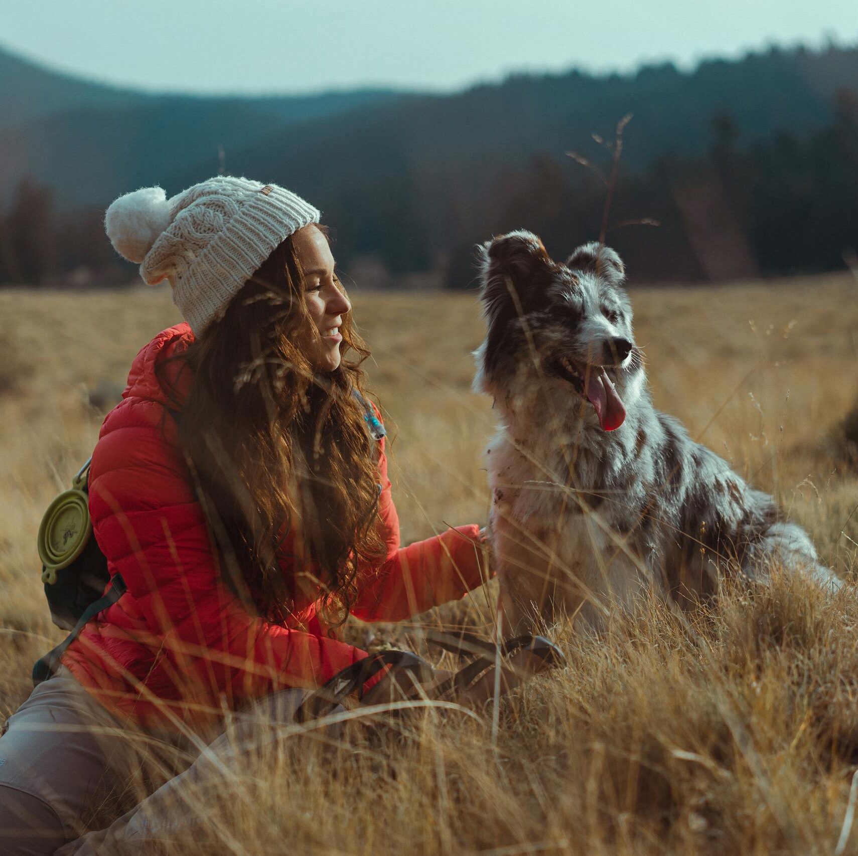 A woman and her dog enjoy a serene outdoor adventure in a grassy field.