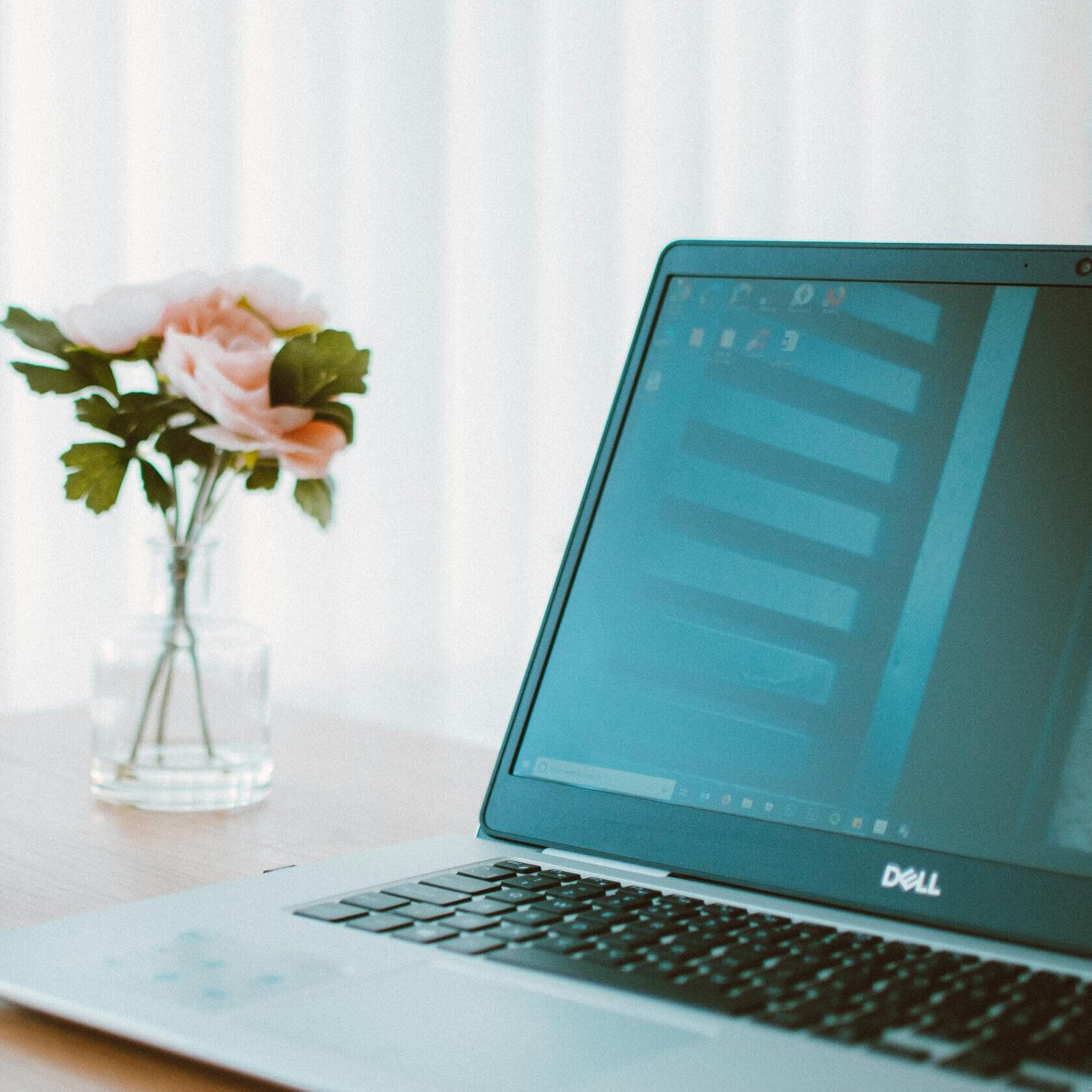 Comfortable home office desk with laptop, coffee mug, and flower vase.