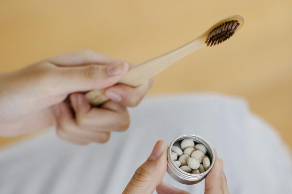 From above of unrecognizable female with toothbrush and pile of toothpaste tablets during daily morning routine at home on blurred background