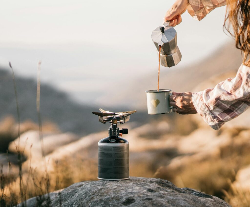 A serene scene of coffee being poured at a campsite, evoking morning tranquility.