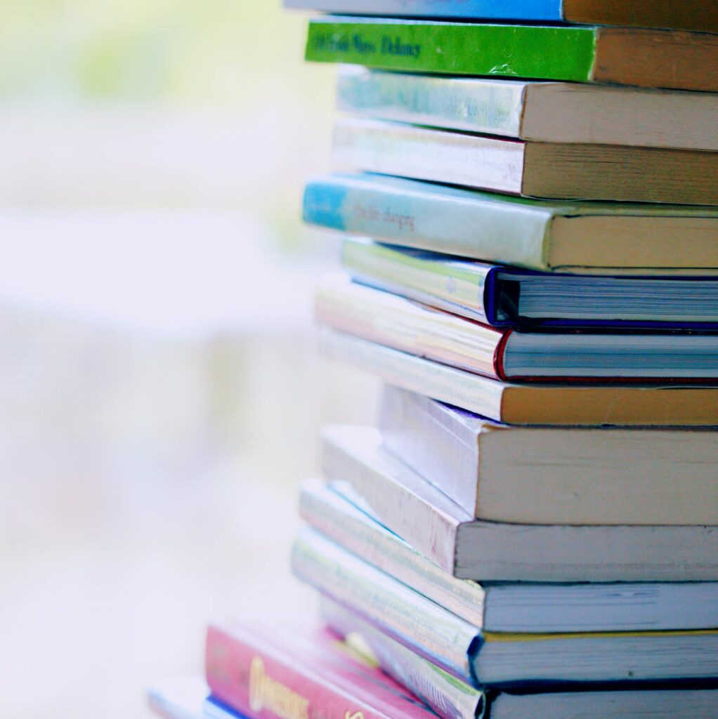 A tall stack of colorful hardcover books on a table indoors, perfect for library-themed concepts.