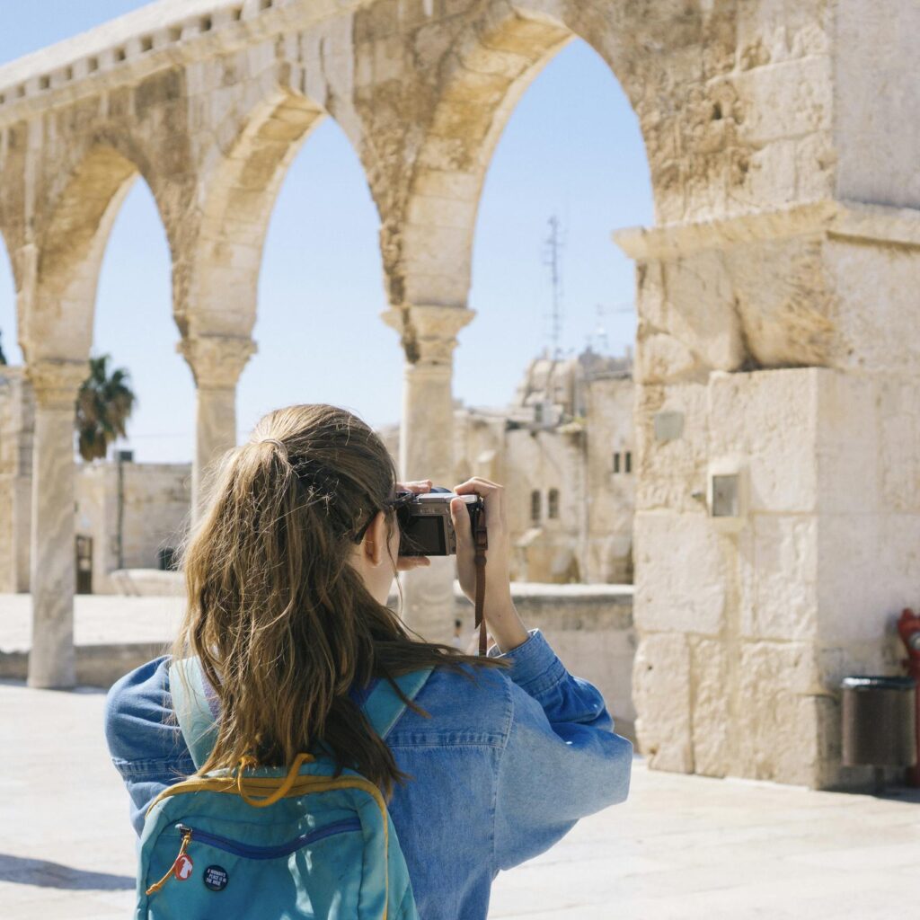 A tourist photographs the ancient stone arches in Jerusalem's Old Town, capturing the essence of travel and history.