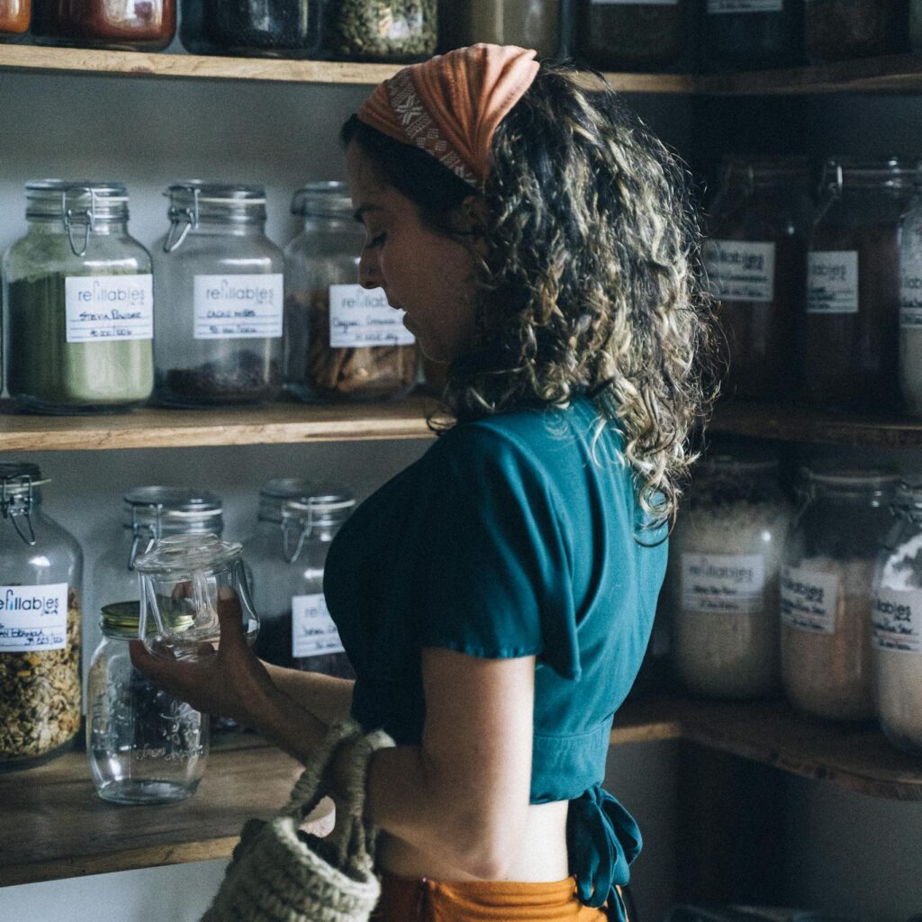A woman browsing glass jars in a zero waste store, highlighting eco-friendly shopping habits.