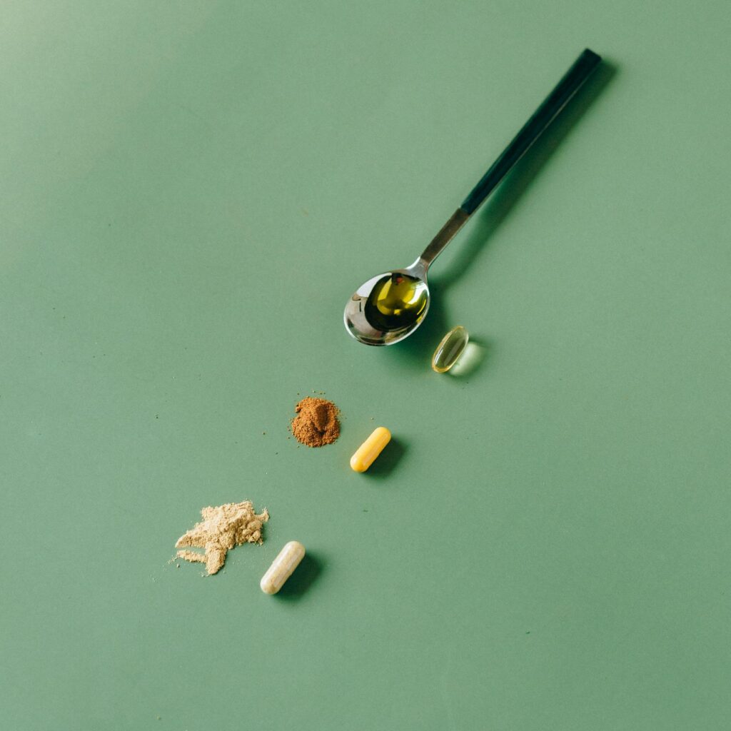 Assorted herbal supplements and powders on a green backdrop with a spoon.