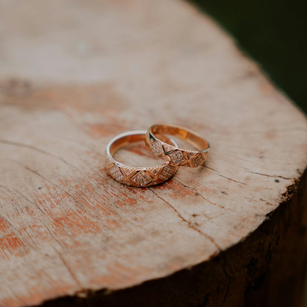 Close-up of two intricate wedding rings on a rustic wooden surface, symbolizing love and commitment.