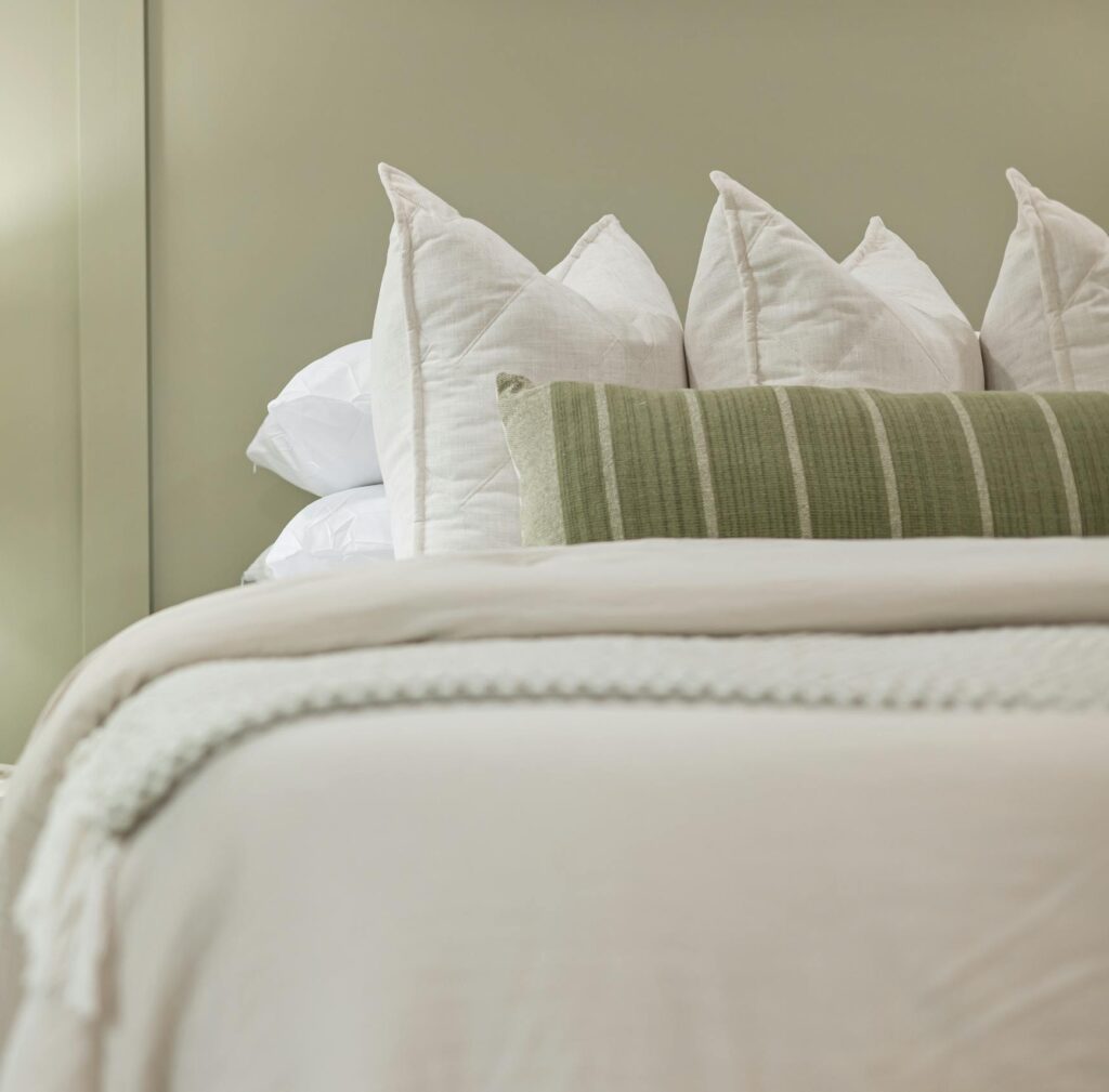 Elegant bedroom scene featuring a modern lamp, plush pillows, and soft bedding for a serene ambiance.