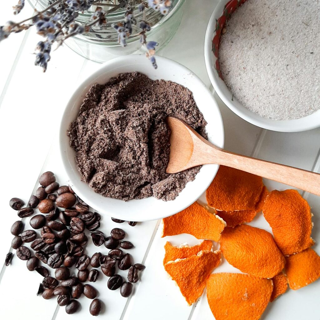Flat lay of coffee beans, orange peel, and natural ingredients on a white background.