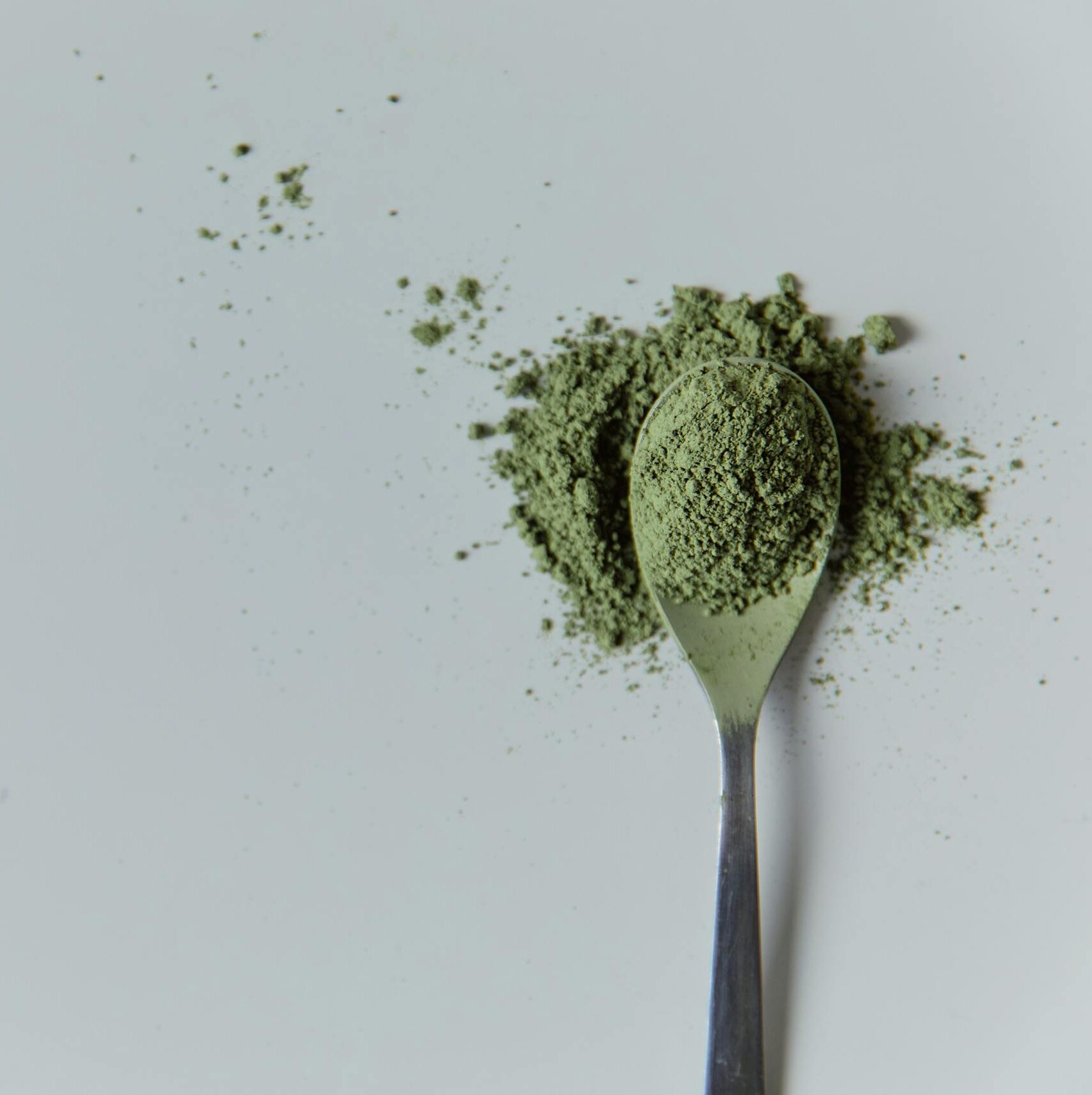 High-quality matcha powder on a spoon in a minimalist studio setting, ideal for culinary and wellness themes.