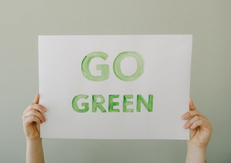 Image of hands holding a 'Go Green' sign to promote environmental awareness and sustainability.