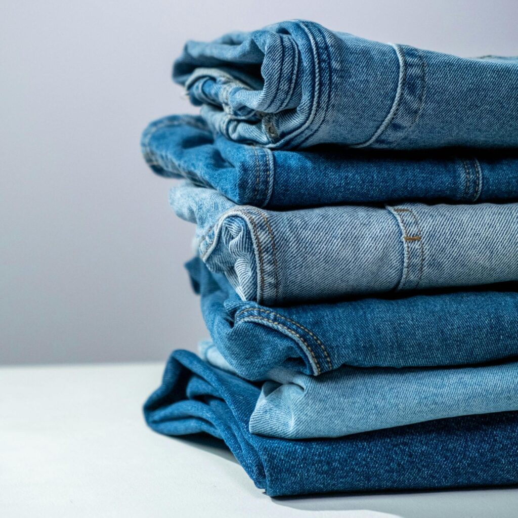 Neatly folded blue denim jeans stacked on a white surface, perfect for fashion or retail themes.