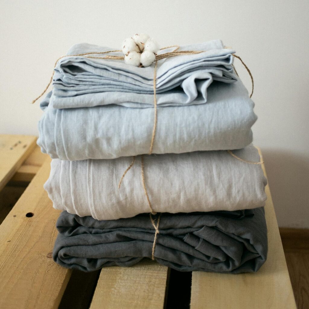 Neatly folded linen blankets tied with cotton on wooden crate, minimal style.