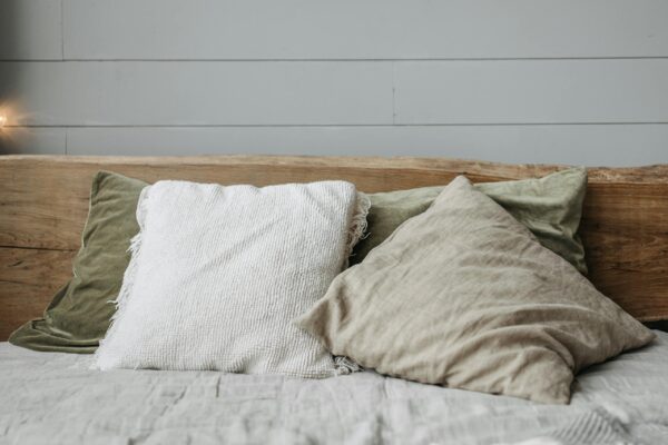 Relaxing bed setting with rustic wooden headboard and cushions.