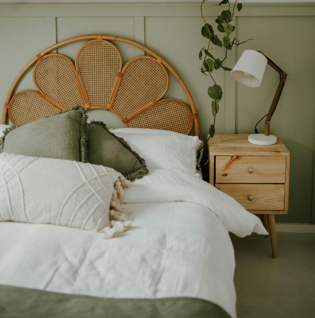 Stylish bedroom with a rattan headboard, green decor, and hanging plants for a serene ambiance.