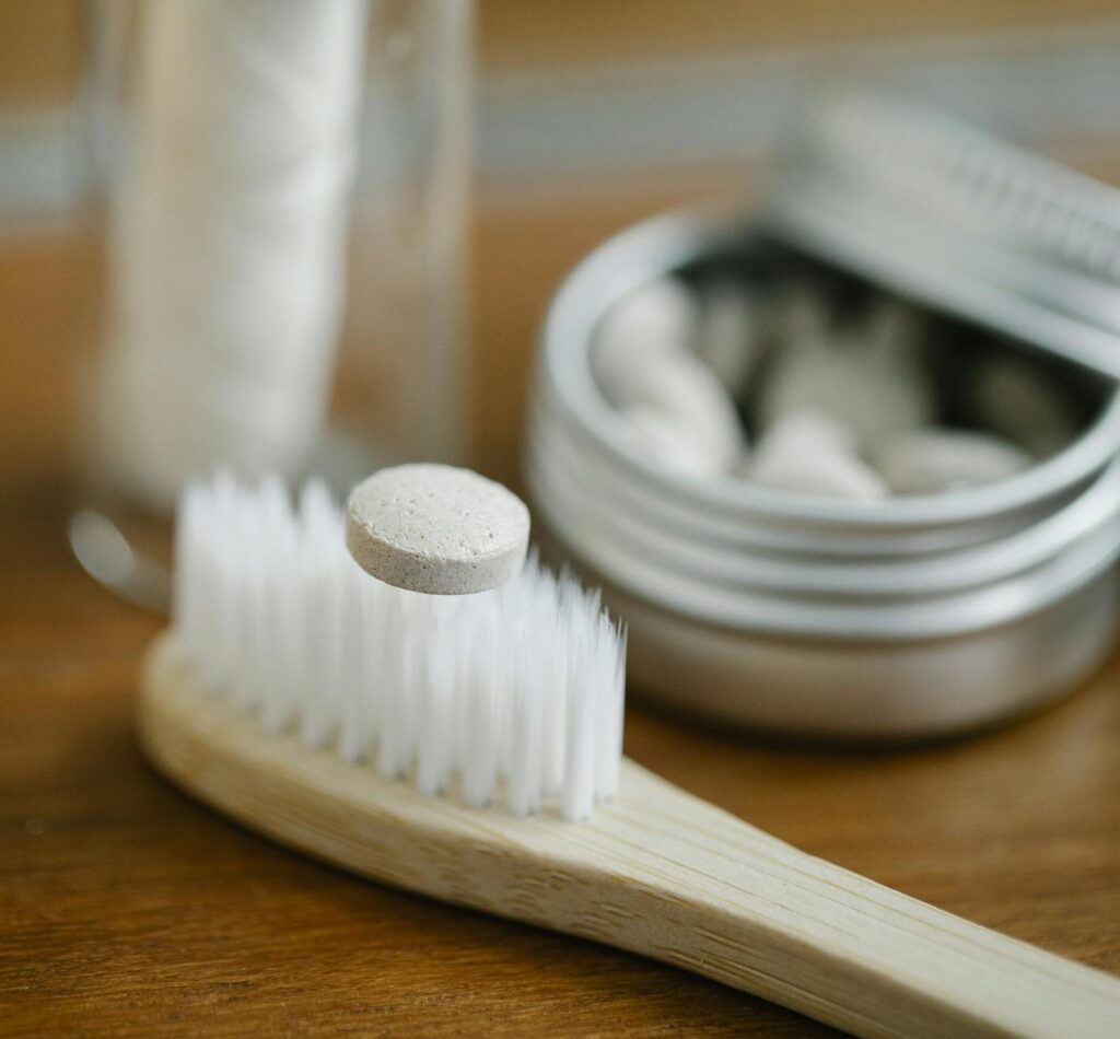 Sustainable wooden toothbrush with dental floss and tablets in a modern bathroom setting.