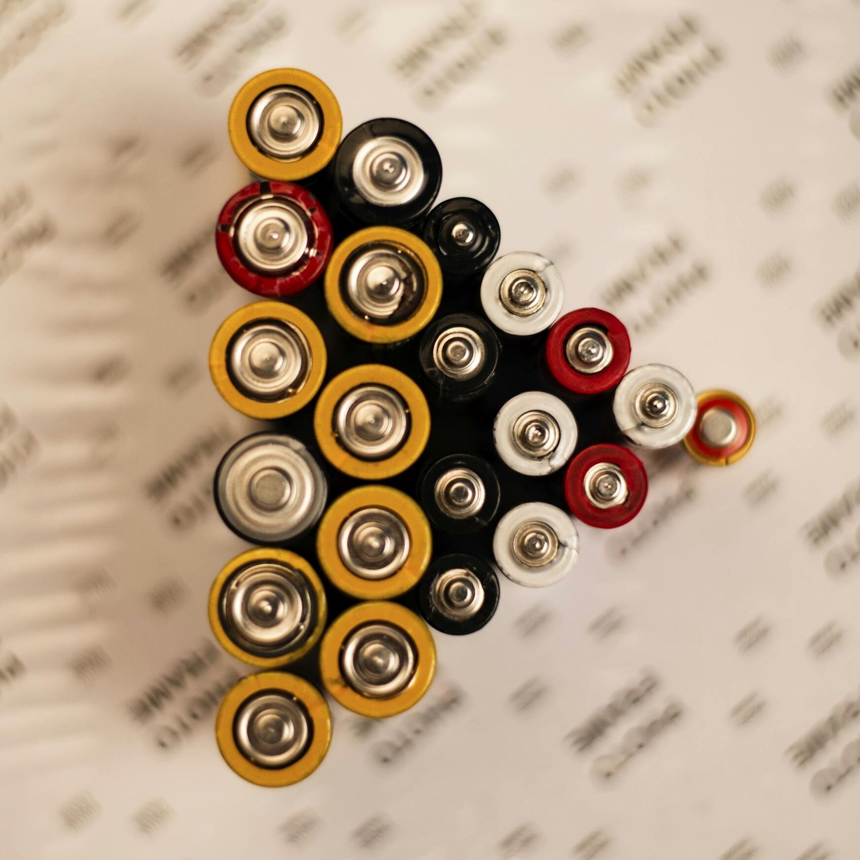 Top view of assorted batteries in an artistic arrangement on a printed surface.
