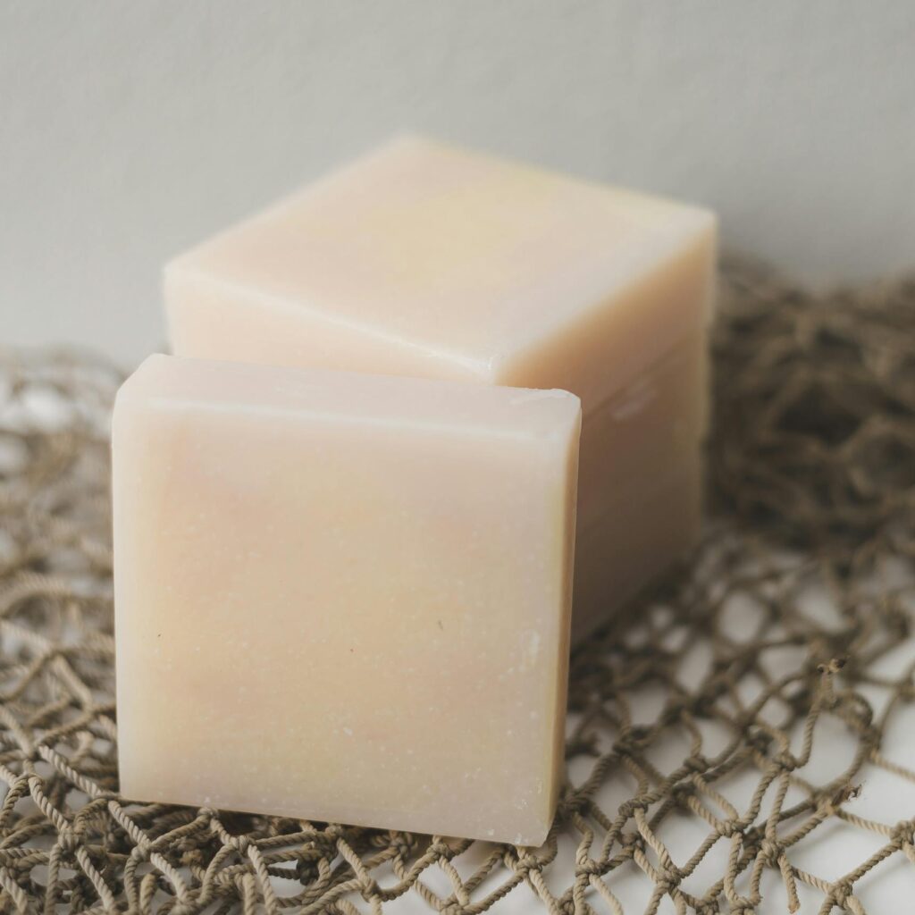 Two bars of natural handmade soap placed on a rustic netting backdrop, perfect for a spa theme.