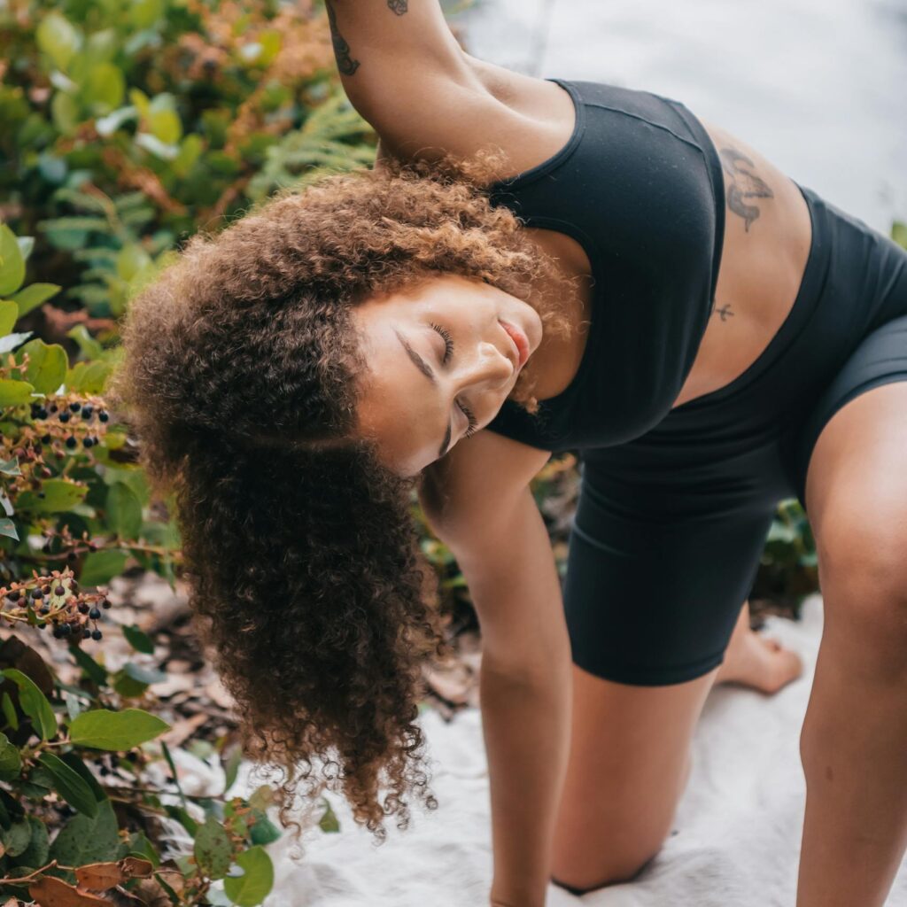 Woman stretching in activewear outdoors by a river, emphasizing wellness and nature.