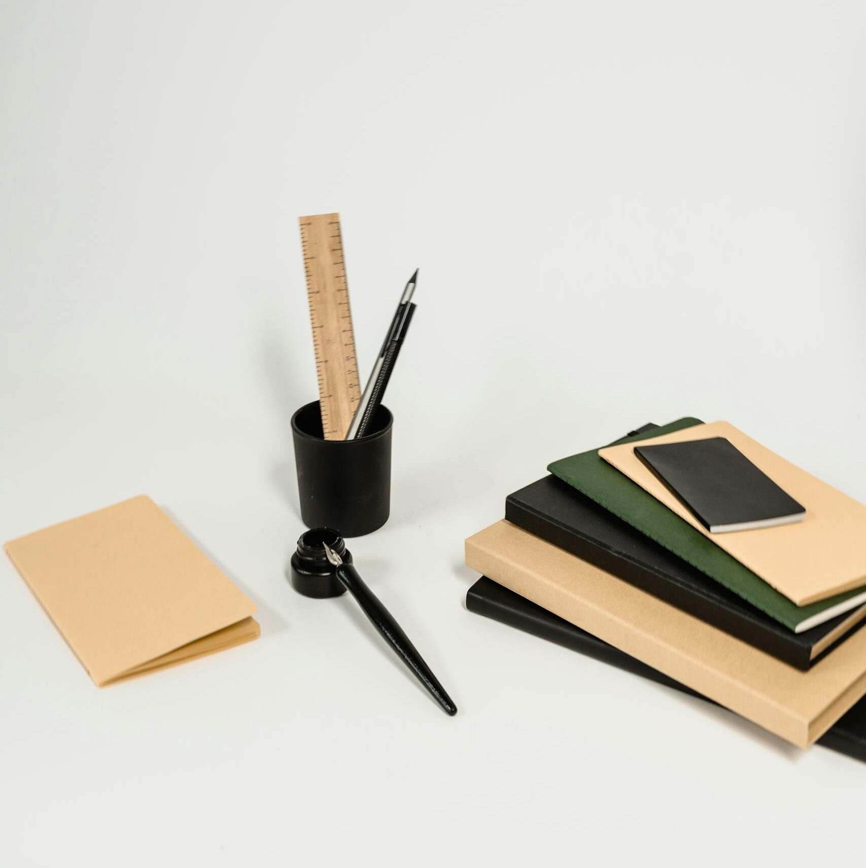 A tidy arrangement of notebooks, pens, and a ruler on a white background, ideal for office themes.