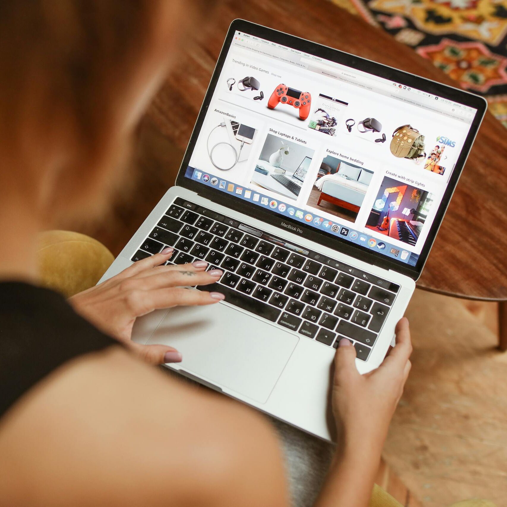 A woman shops online on her laptop while seated in a cozy home environment.