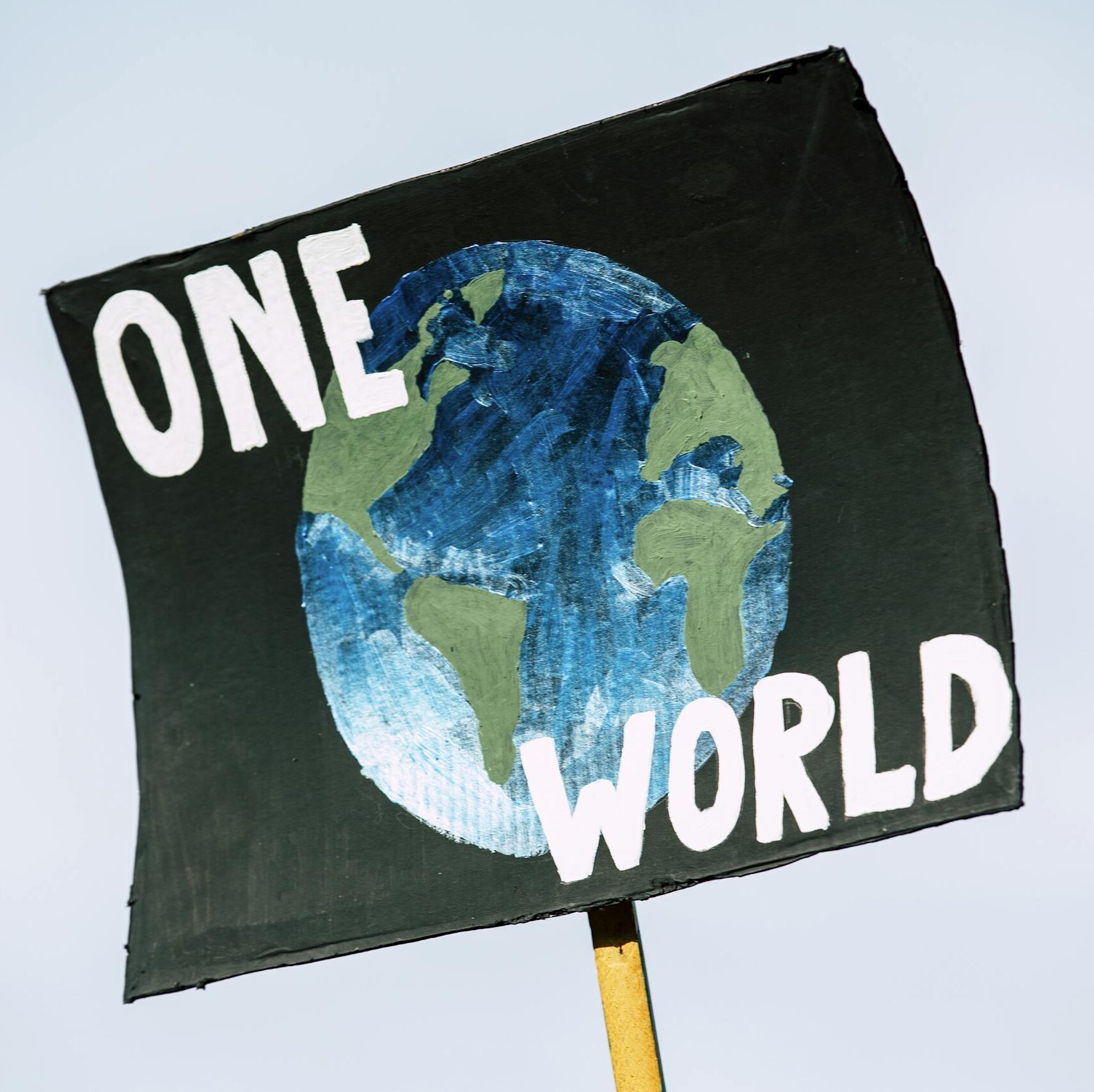 Close-up of a protest sign with Earth and 'One World' text, symbolizing climate change awareness.