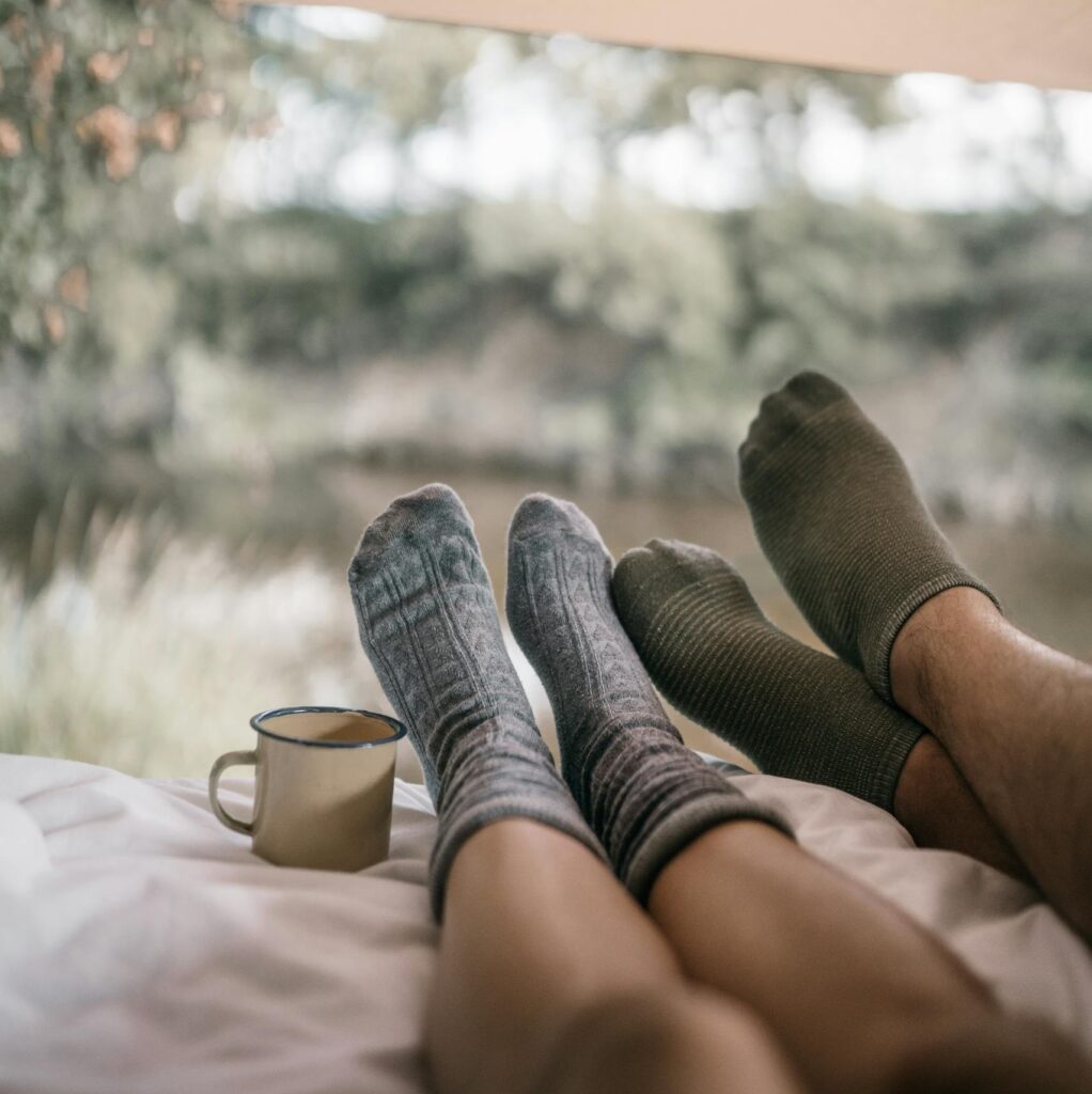 Enjoy a tranquil day camping with cozy socks and a warm drink in the heart of nature.