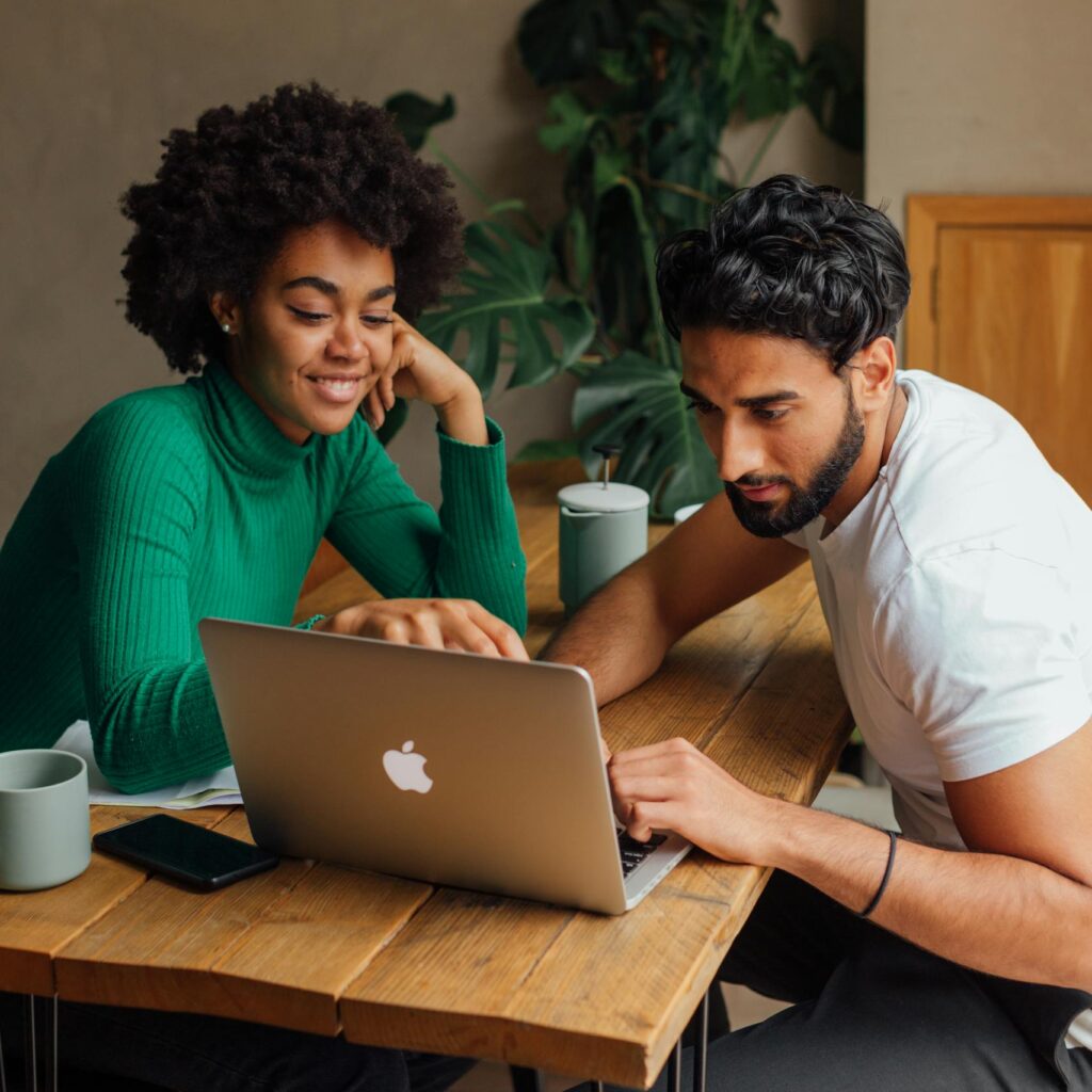 Two colleagues collaborating on a project using a laptop in a modern office setting.
