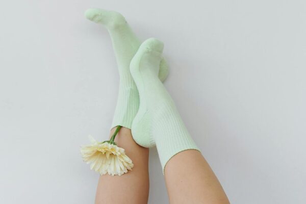 Whimsical and artistic shot of legs upside down in green socks with a flower, creating a minimalist and playful vibe.