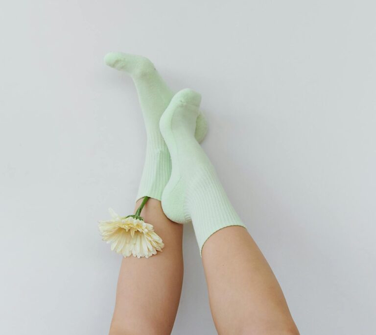 Whimsical and artistic shot of legs upside down in green socks with a flower, creating a minimalist and playful vibe.