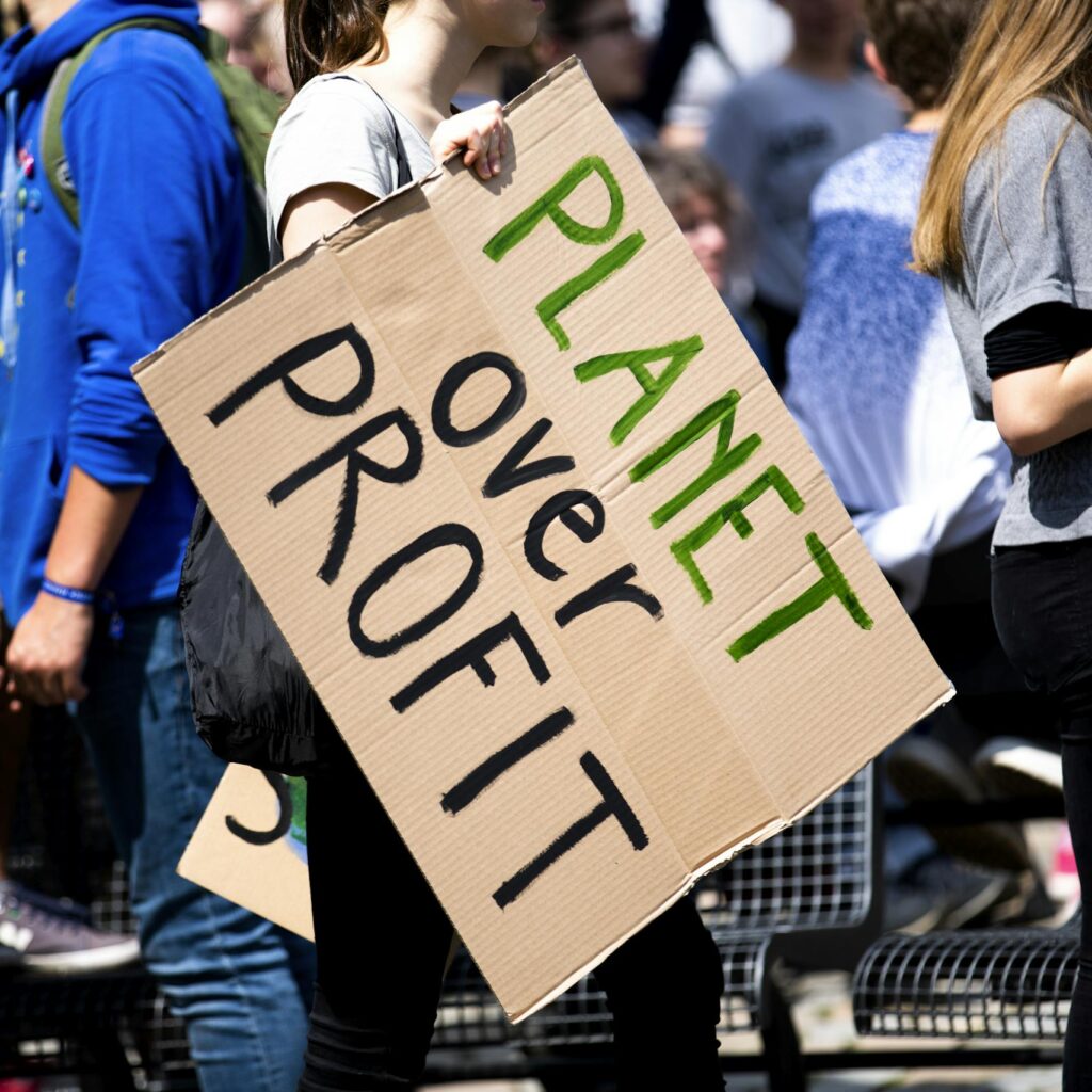 Youth climate protest with participants holding 'Planet Over Profit' sign.