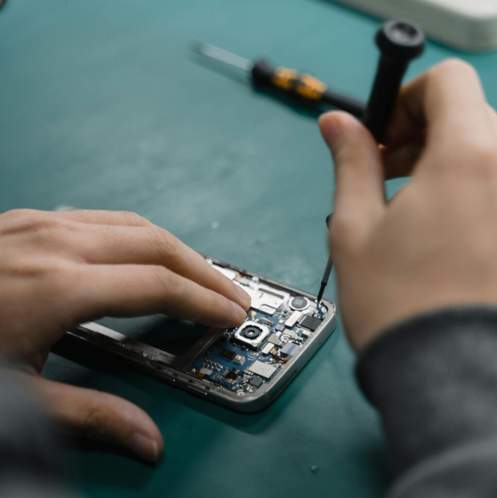 A focused view of repairing a smartphone circuit board with tools by hand.