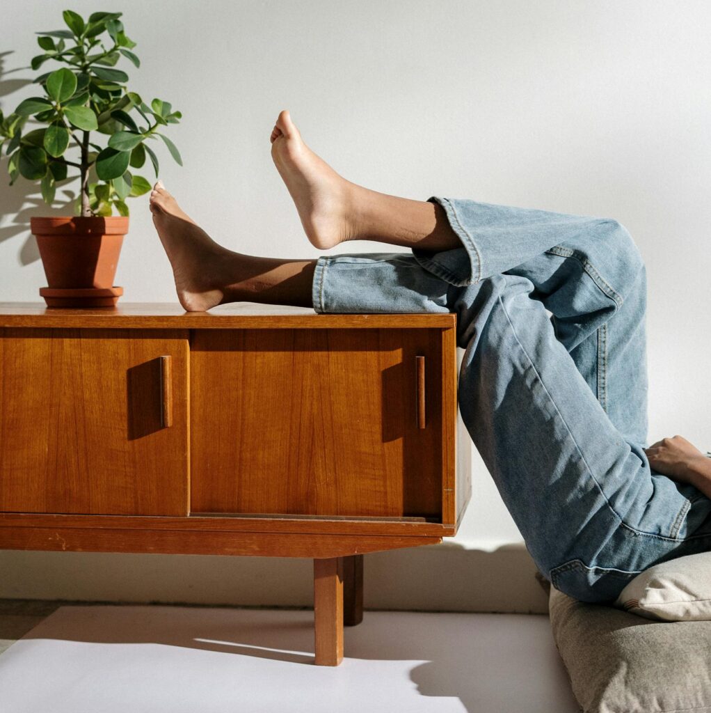 Casual lifestyle scene with bare feet and denim in a cozy interior.