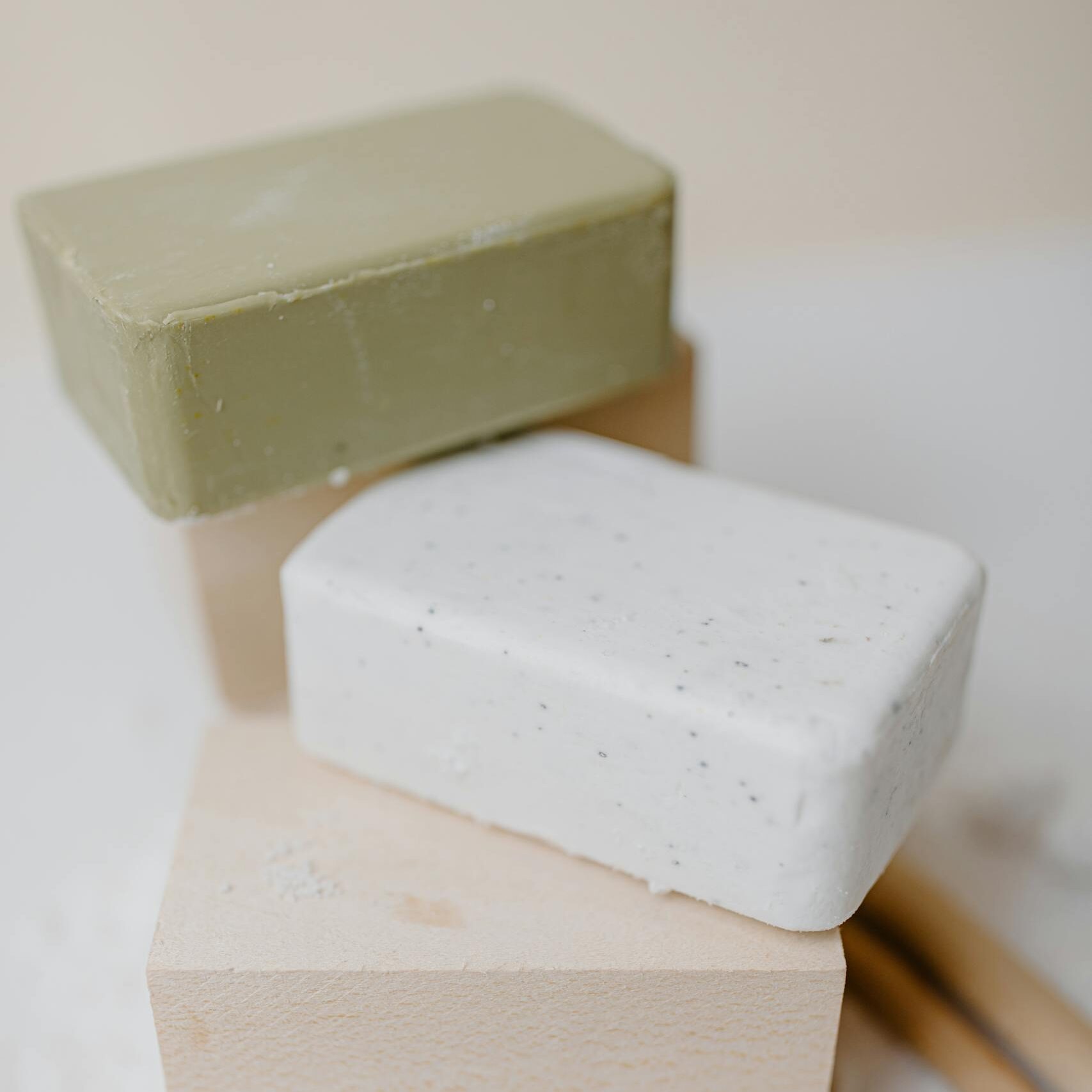 Three bars of organic soap stacked on wooden blocks, showcasing purity and minimalism.