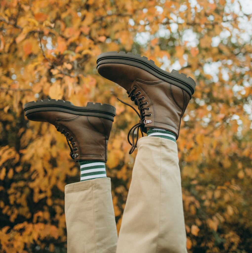 Brown boots and striped socks in a playful autumn scene with golden foliage.