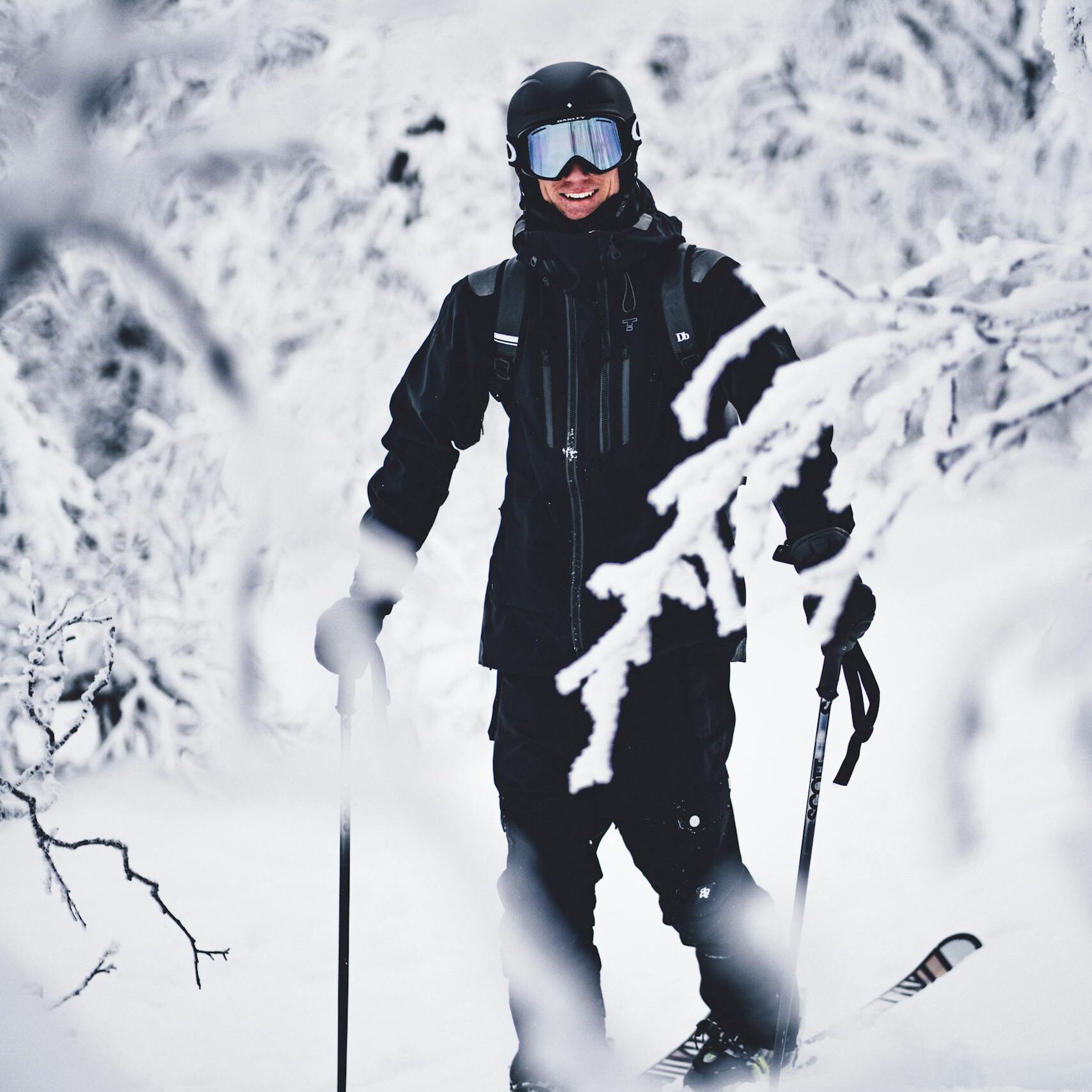 A cheerful skier in full gear smiling amidst a snowy forest landscape.