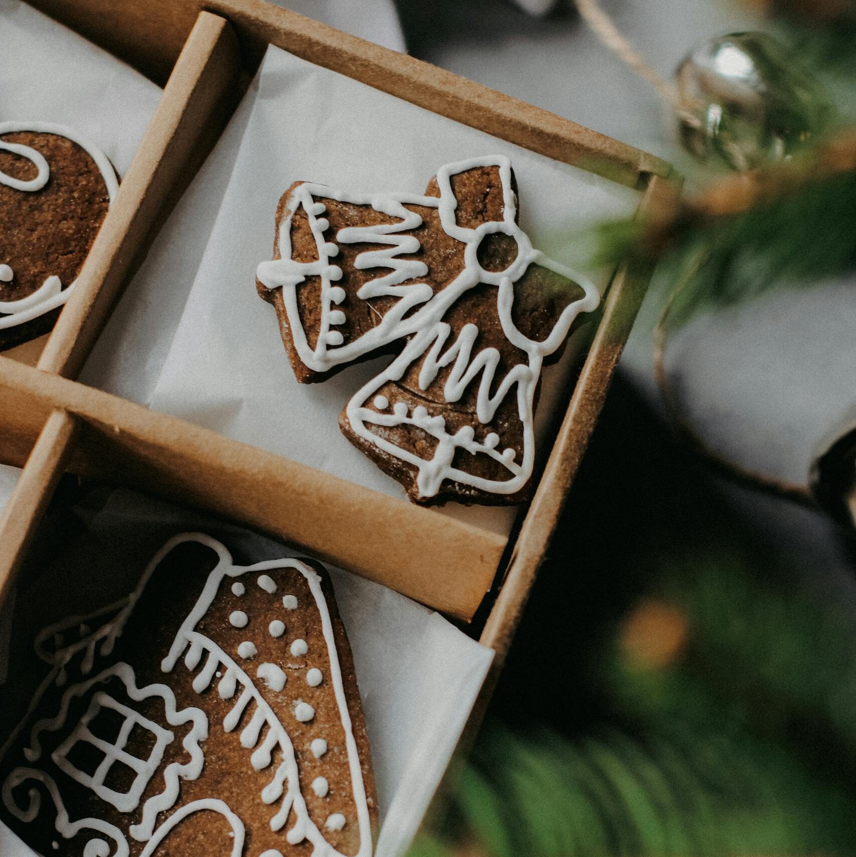 Gingerbread cookies decorated with icing in a Christmas-themed box, perfect for holiday celebrations.
