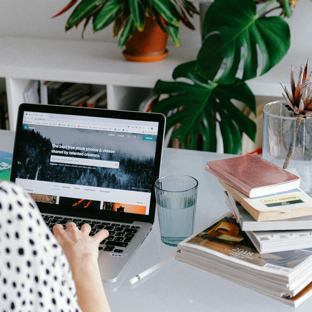 A woman working from home on her laptop surrounded by plants and books for a cozy office feel.