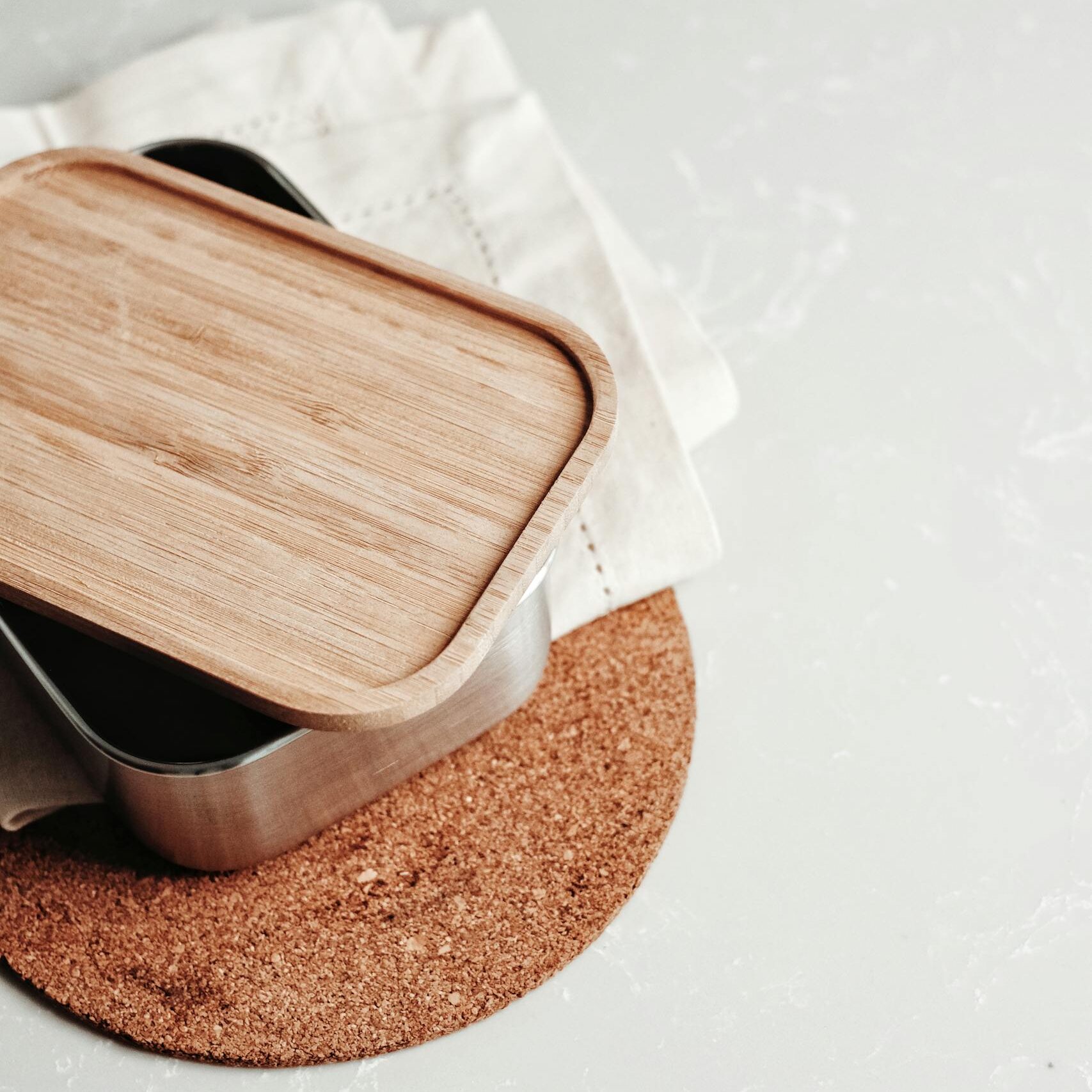 Minimalist design of a sustainable bamboo lid container on a cork mat.
