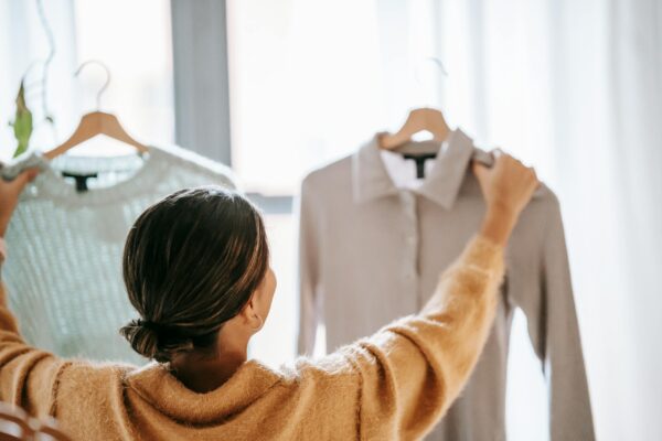 A woman deciding between two stylish outfits in a cozy boutique setting.