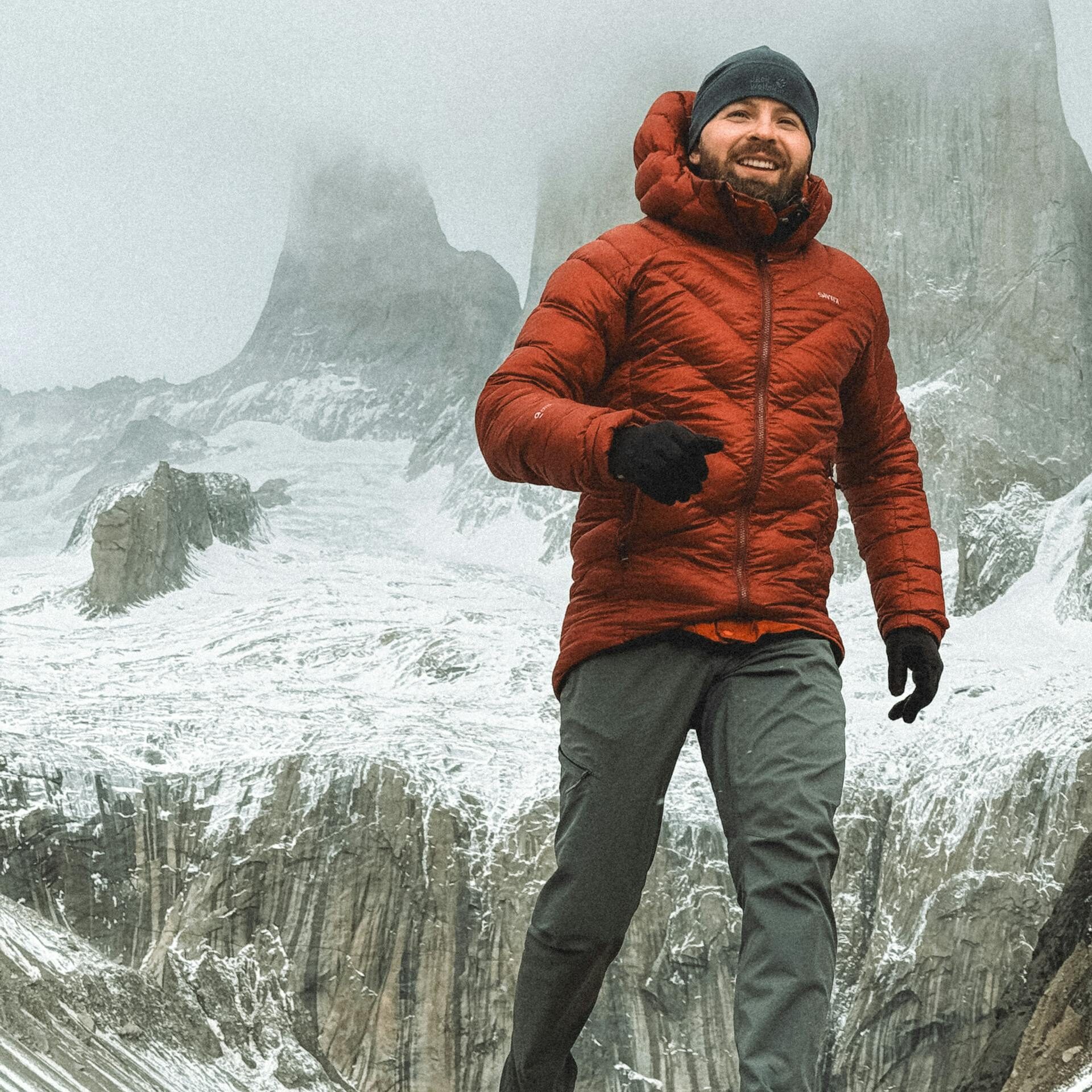 Man hiking in Torres del Paine, Chile, wearing warm clothing in a snowy mountain landscape.