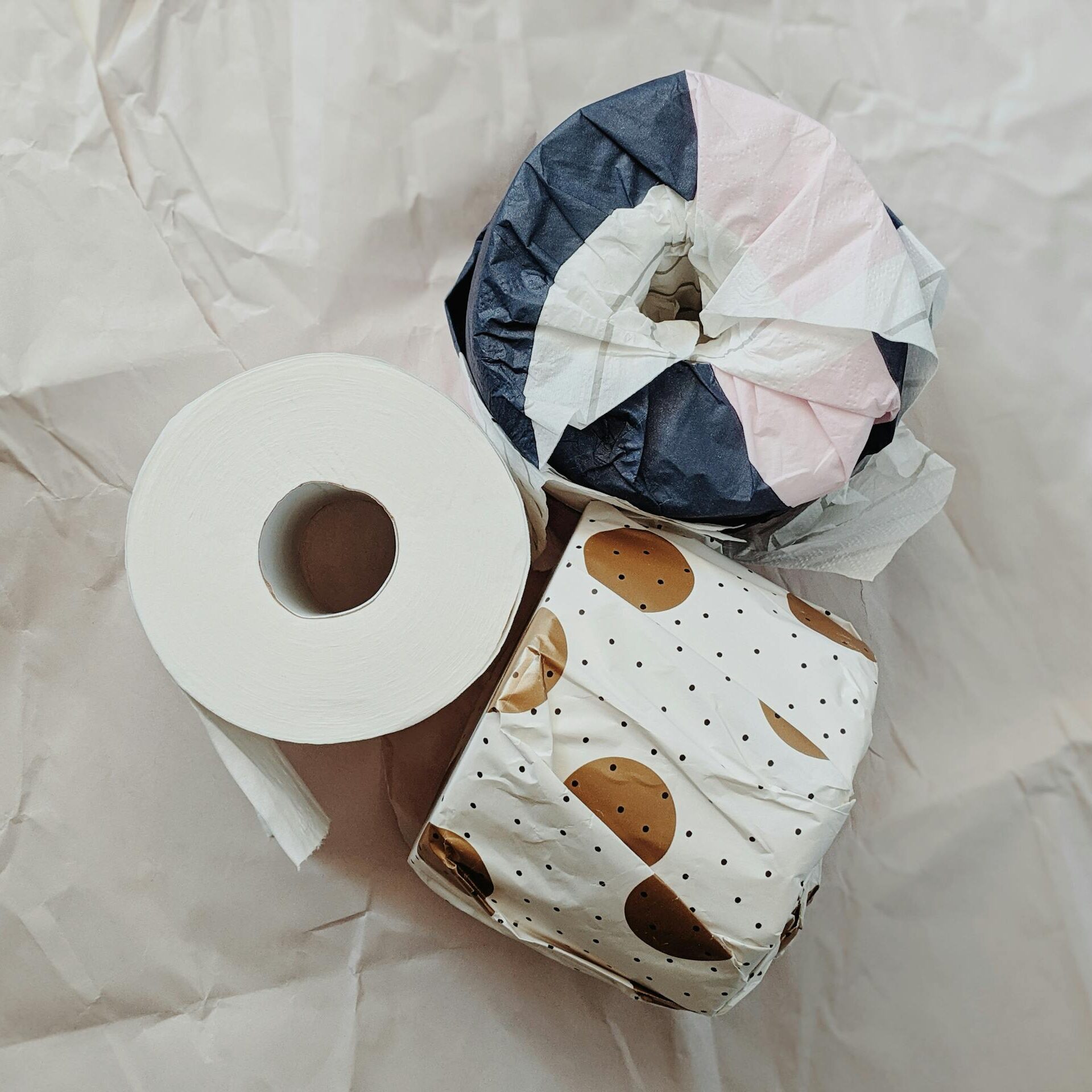 Aesthetic arrangement of wrapped toilet paper rolls on a neutral background, showcasing minimalism.
