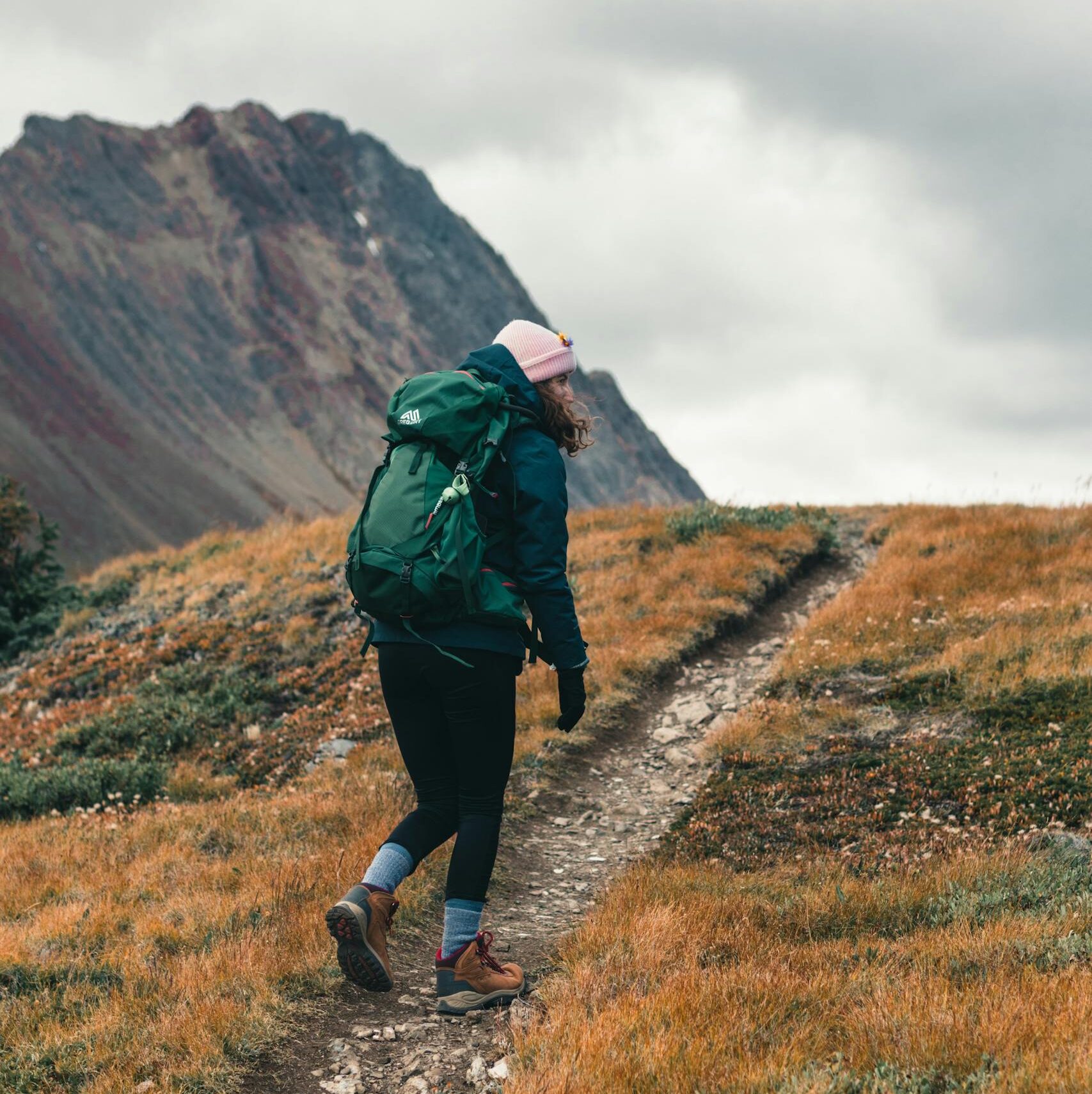 Woman hiker with backpack trekking a mountain trail in Jasper National Park, Canada.