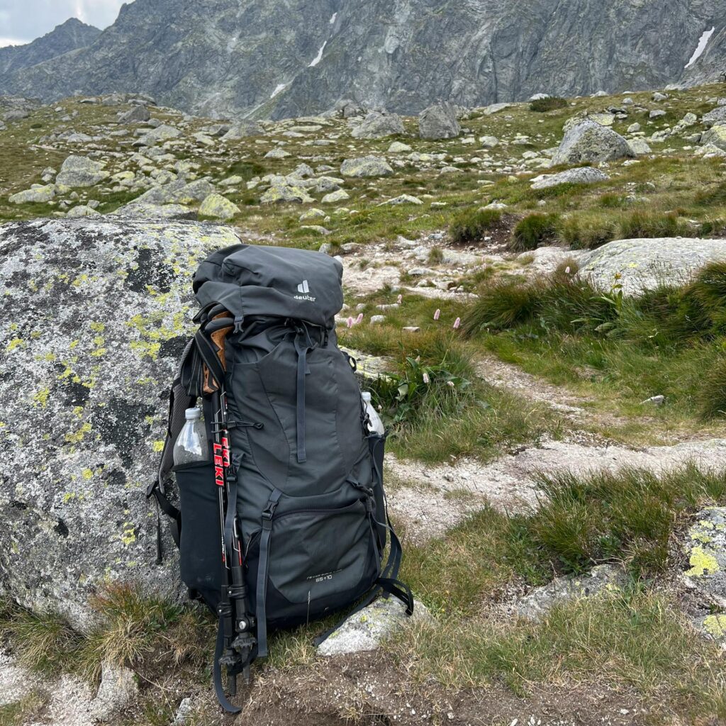 A hiking backpack resting on rocky terrain with Tatra Mountains in the background.